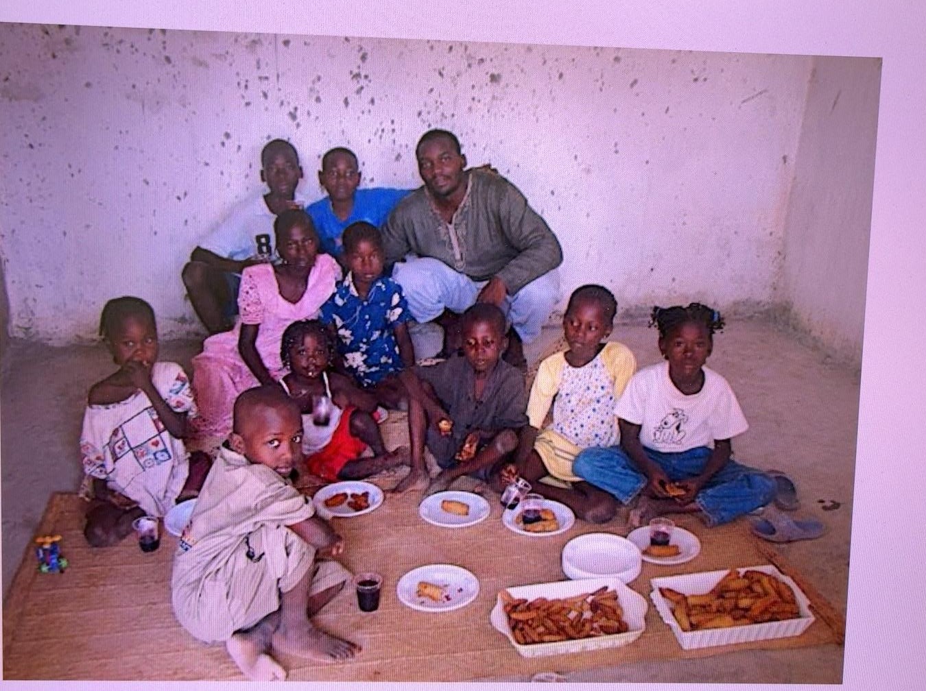Children and a caregiver sharing a meal together in Cameroon